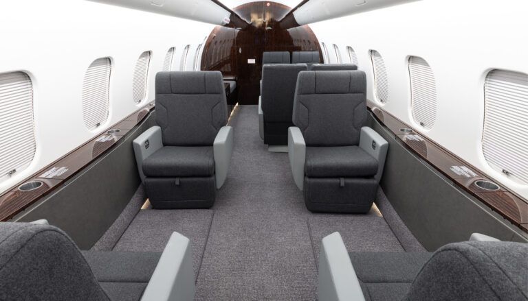 Private jet interior with grey seats and dark veneer