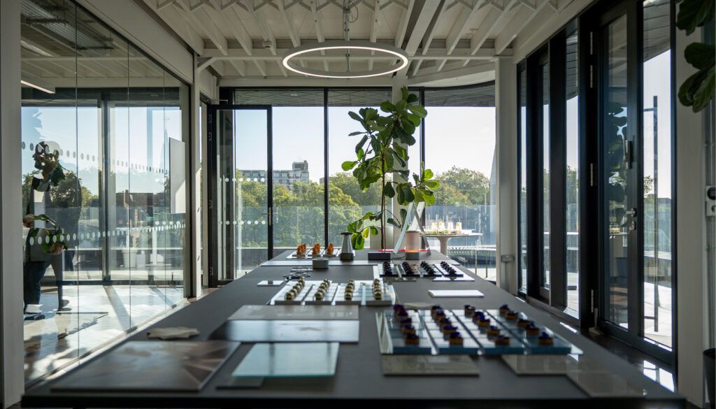 Modern glass-walled meeting room with exhibits and canapes on table