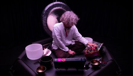 Person using electronic music equipment with singing bowls