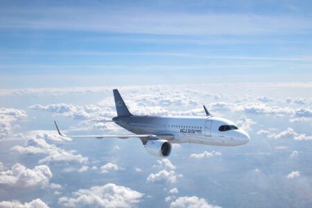 ACJ319neo aircraft flying above clouds in bright blue sky