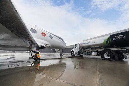 Aircraft being refueled by tanker truck on wet tarmac