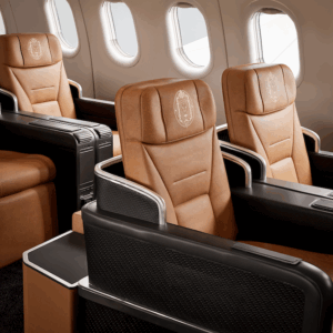 Tan leather business class seats with embossed emblems and windows.