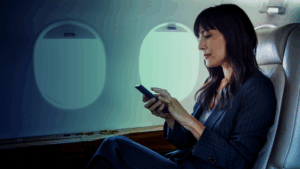 Woman using smartphone on airplane in evening ambient lighting