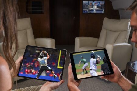 Two people watching sports on tablets in luxury aircraft cabin