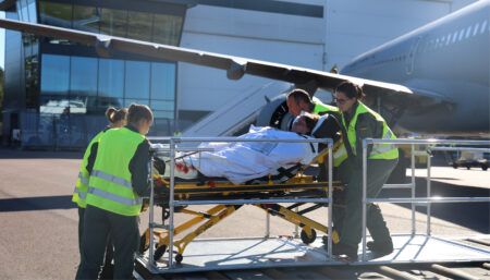 Medical staff loading patient on stretcher into aircraft