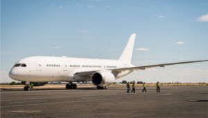 Ground crew walking past white Boeing 787 on tarmac