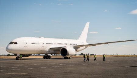 Ground crew walking past white Boeing 787 on tarmac