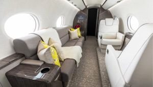 Private jet lounge area with grey divan and cream seats