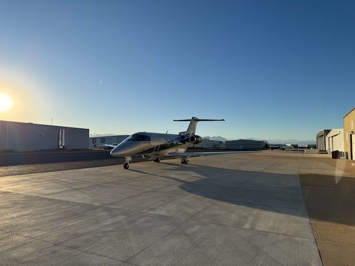 Gogo begins testing 5G air-to-ground connectivity White private jet parked on airport tarmac at sunset with hangars in background