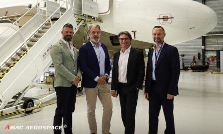 Four business professionals posing in aircraft hangar near jet