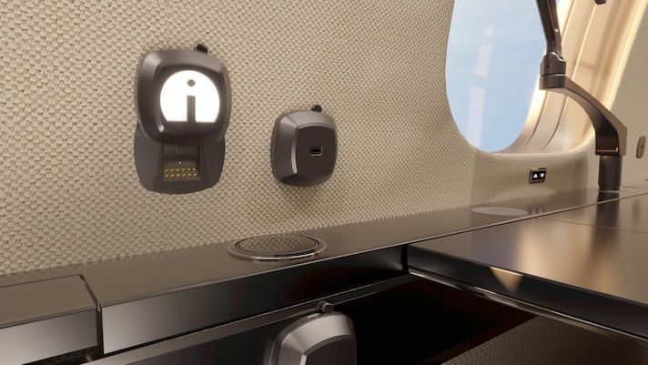 Ingenio Aerospace launches interchangeable connectivity ecosystem Close-up of aircraft workspace showing charging ports mounted on textured wall panel beside window and desk with reading light