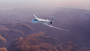 White private jet flying over dramatic desert canyon landscape at dusk with purple and pink sky
