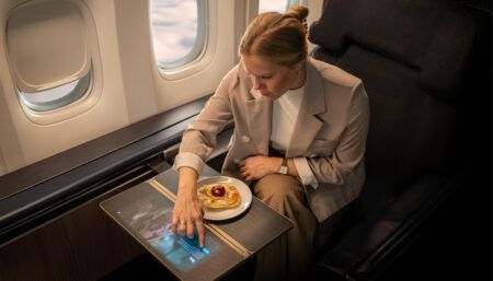 Touchscreen functionality integrated into table surface by Lufthansa Technik Private jet passenger interacting with touchscreen in tray table surface