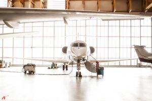 Private jet front view in bright modern aircraft hangar