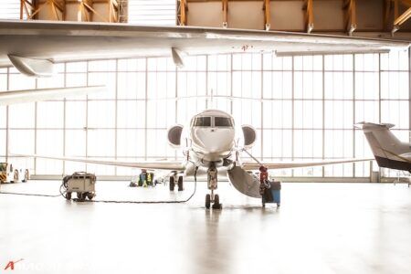 Private jet front view in bright modern aircraft hangar