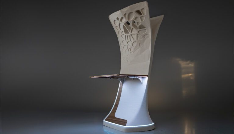 Mockup of sculptural cabin structure with complex, organic-looking decorative pattern of perforations and recesses, and attached table