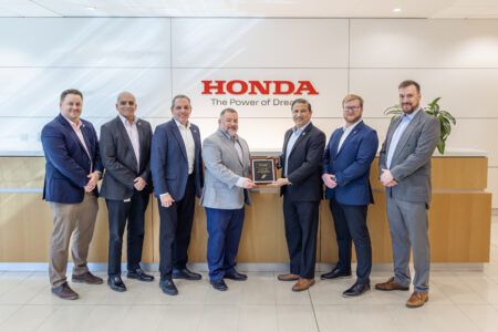 Straight Flight appointed HondaJet ASC for northwest US Seven business professionals standing in corporate reception area beneath Honda company logo and tagline, with two men in centre holding framed certificate