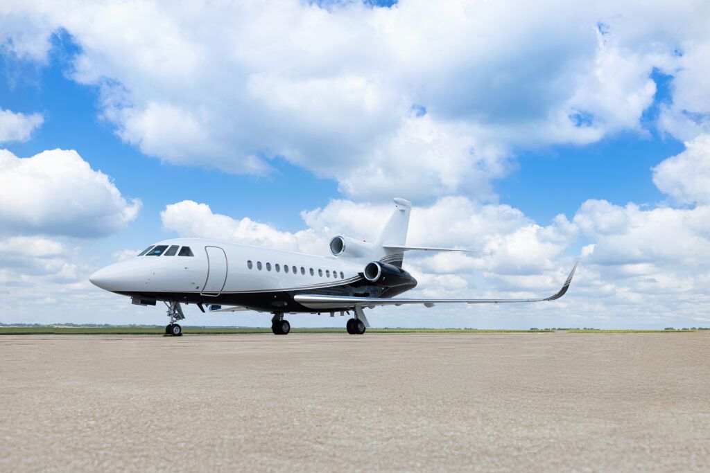 Dassault Falcon 900EX trijet business aircraft on tarmac with white and black paint scheme featuring stripe along fuselage