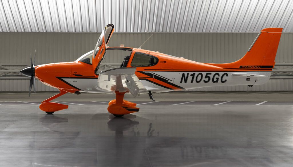 Orange and white single-engine piston aircraft in hangar