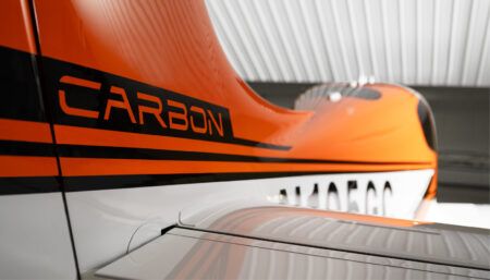 Close-up of orange and white aircraft fuselage with black stripes
