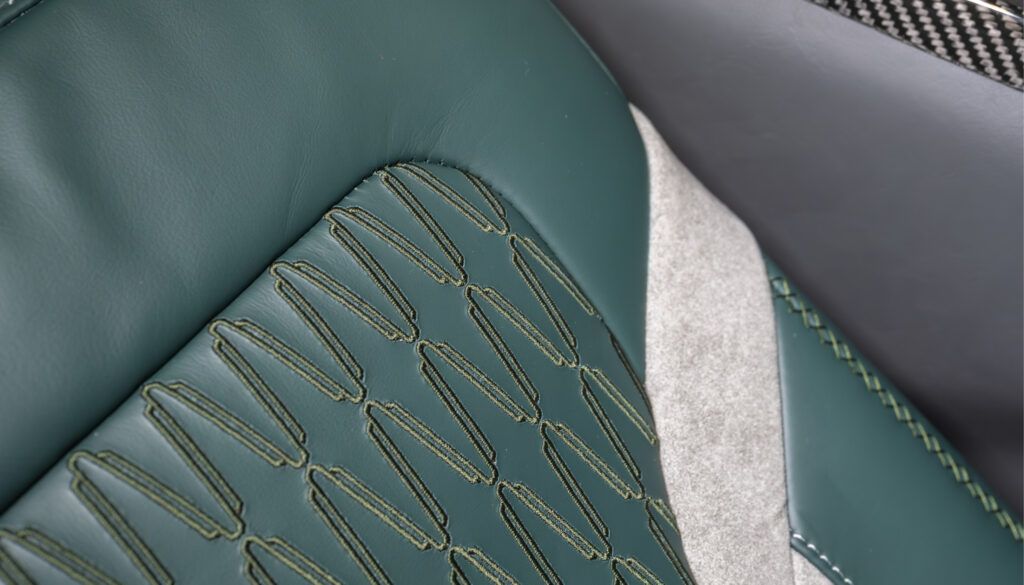 Close-up of decorative stitching pattern on green leather aircraft seat