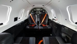 TBM 980 aircraft interior with black seats and orange seatbelts