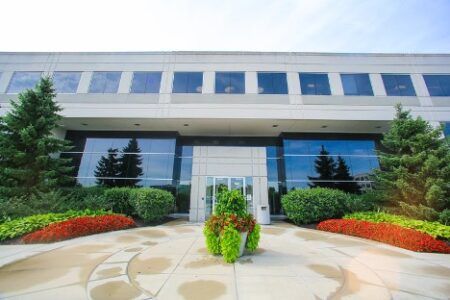 Modern glass-fronted office building with landscaped entrance and decorative planter