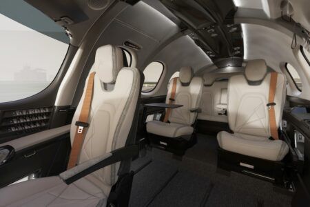 Cirrus G3 Vision Jet cabin interior showing cream seats, tray tables, and seven-seat configuration including third-row bench seat