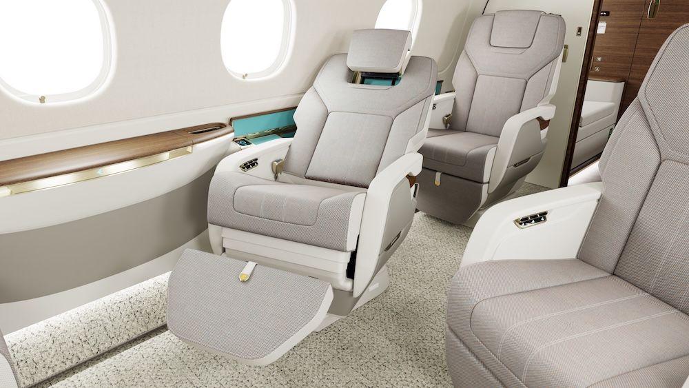 Three business jet seats shown in a light grey and cream interior, with one seat fully reclined and the leg rest extended.