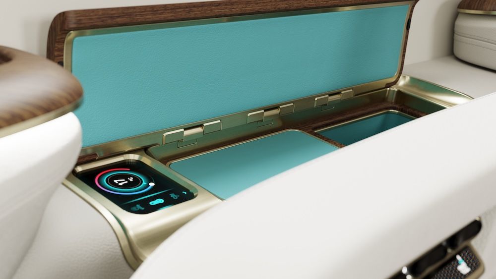 Close-up of an open business jet sideledge storage compartment showing turquoise-coloured lining with gold trim, and a circular touchscreen seat control panel.