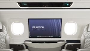 Praetor 600E business jet sidewall with 42in OLED display mounted between two oval windows, showing the Praetor by Embraer logo on screen, and overhead upper tech panel