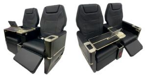 Two render views of the Starling Aerospace SA5000 corporate aircraft seat in black leather with gold-tone fittings, showing extended footrests, fold-out tables and tablet holders
