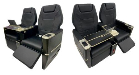 Two render views of the Starling Aerospace SA5000 corporate aircraft seat in black leather with gold-tone fittings, showing extended footrests, fold-out tables and tablet holders