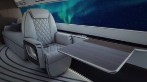 Side-view rendering of the Phantom 3500’s concept cabin showing a quilted leather seat beside an extended work table, with digital displays creating a wraparound view of the northern lights against a starlit sky.