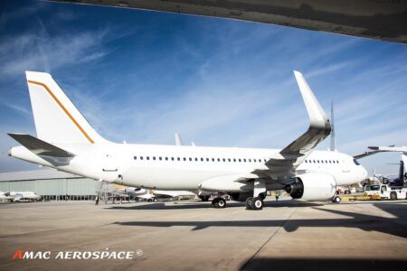 A white ACJ320 with an orange tail stripe at airport