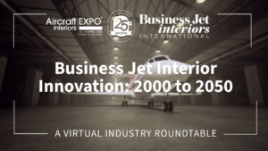 Thumbnail graphic for a virtual industry roundtable titled 'Business Jet Interior Innovation: 2000 to 2050', hosted by Business Jet Interiors International in partnership with Aircraft Interiors Expo 25th Edition, held 14-16 April 2026 in Hamburg, Germany. The background shows a business jet parked inside a large aircraft hangar, with moody, low-contrast lighting. Text and logos appear in white against the darkened image.
