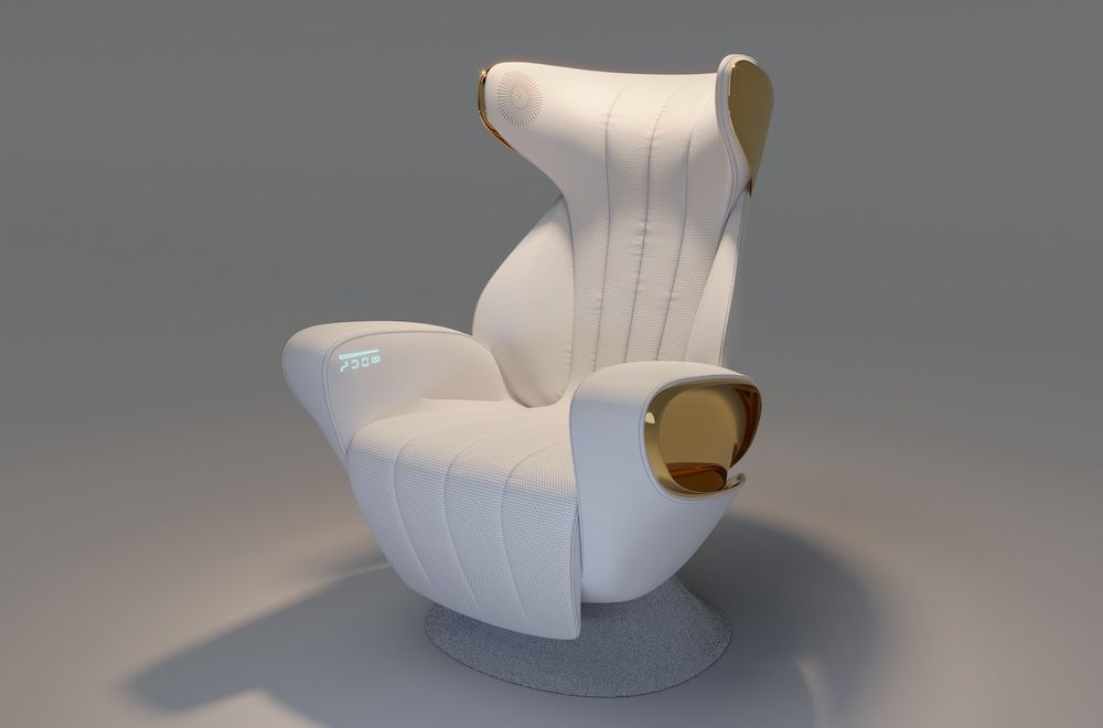 A render of a futuristic private aviation seat in white upholstery with gold metallic accents. The sculptural high-backed chair features an organic, wraparound form with vertical channel stitching, a small integrated display on the armrest and a speaker unit set into the side of the head rest.