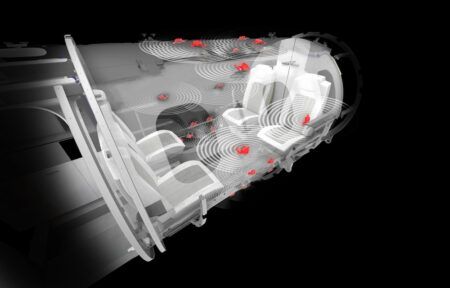 A technical cutaway rendering of a private jet cabin illustrating speaker placement and sound wave propagation. Concentric circular ripples spread from multiple red-highlighted audio transducer positions across the cabin ceiling and walls, visualising the acoustic coverage of a cabin audio system against a dark background.