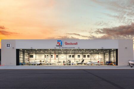 Textron Aviation opens new service facility at Essendon Fields Exterior view of a Textron Aviation service hangar, showing Cessna and Beechcraft branding and multiple aircraft visible inside the open hangar doors at dusk.