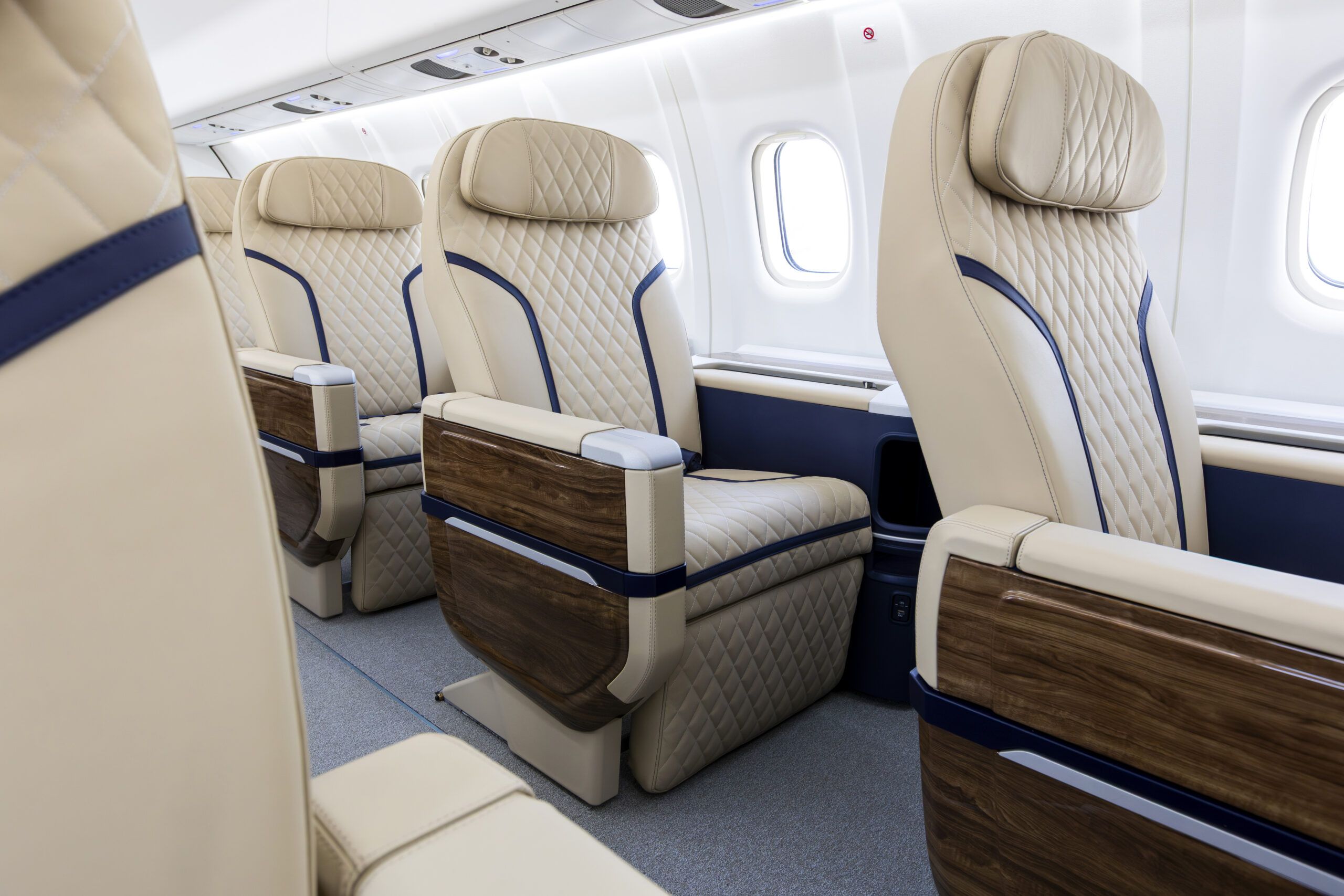 Cream quilted leather seats with walnut armrests in aircraft cabin