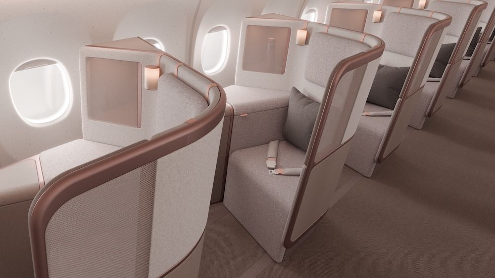 Render of a premium-class aircraft interior showing a row of individual seats, viewed from the aisle looking towards the rear. Each seat is upholstered in a textured warm grey fabric and framed by sculpted shell surrounds with rose gold toned trim detailing. Cylindrical reading lights are mounted by each head rest.