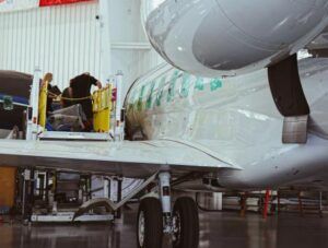 A Gulfstream G650 business jet undergoing inspection inside a Duncan Aviation hangar, with technicians working on an open service door via an access platform alongside the fuselage