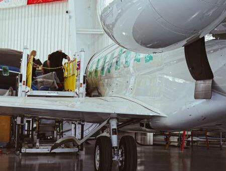 A Gulfstream G650 business jet undergoing inspection inside a Duncan Aviation hangar, with technicians working on an open service door via an access platform alongside the fuselage