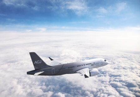 Render of an ACJ TwoTwenty business jet in flight above a layer of cloud, in a white livery with a dark grey tail and rear fuselage carrying the ACJ branding