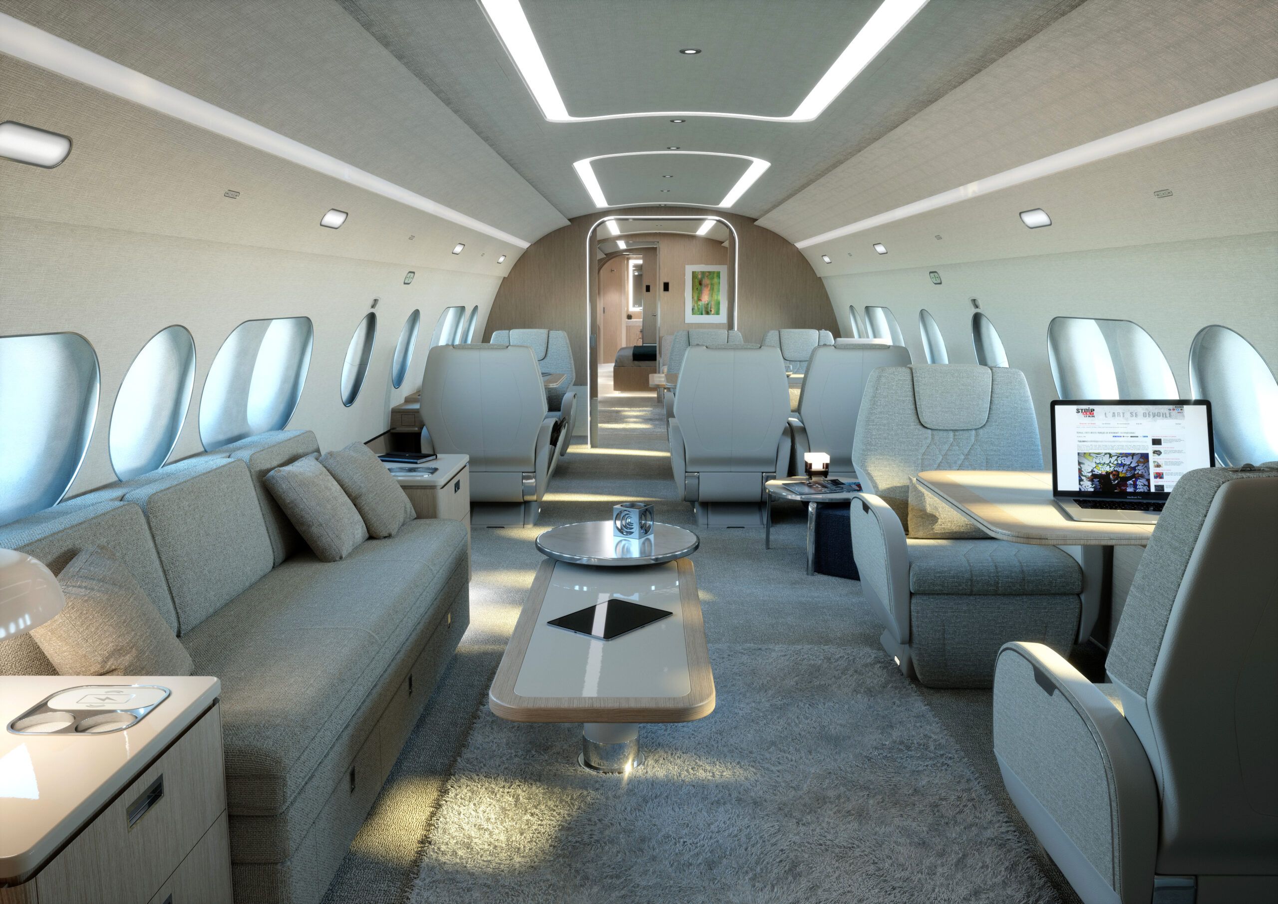 Render of the ACJ TwoTwenty cabin interior showing a business lounge configuration with grey upholstered seating, a sofa, low tables, a workstation with a laptop, and a corridor leading toward a private suite at the rear