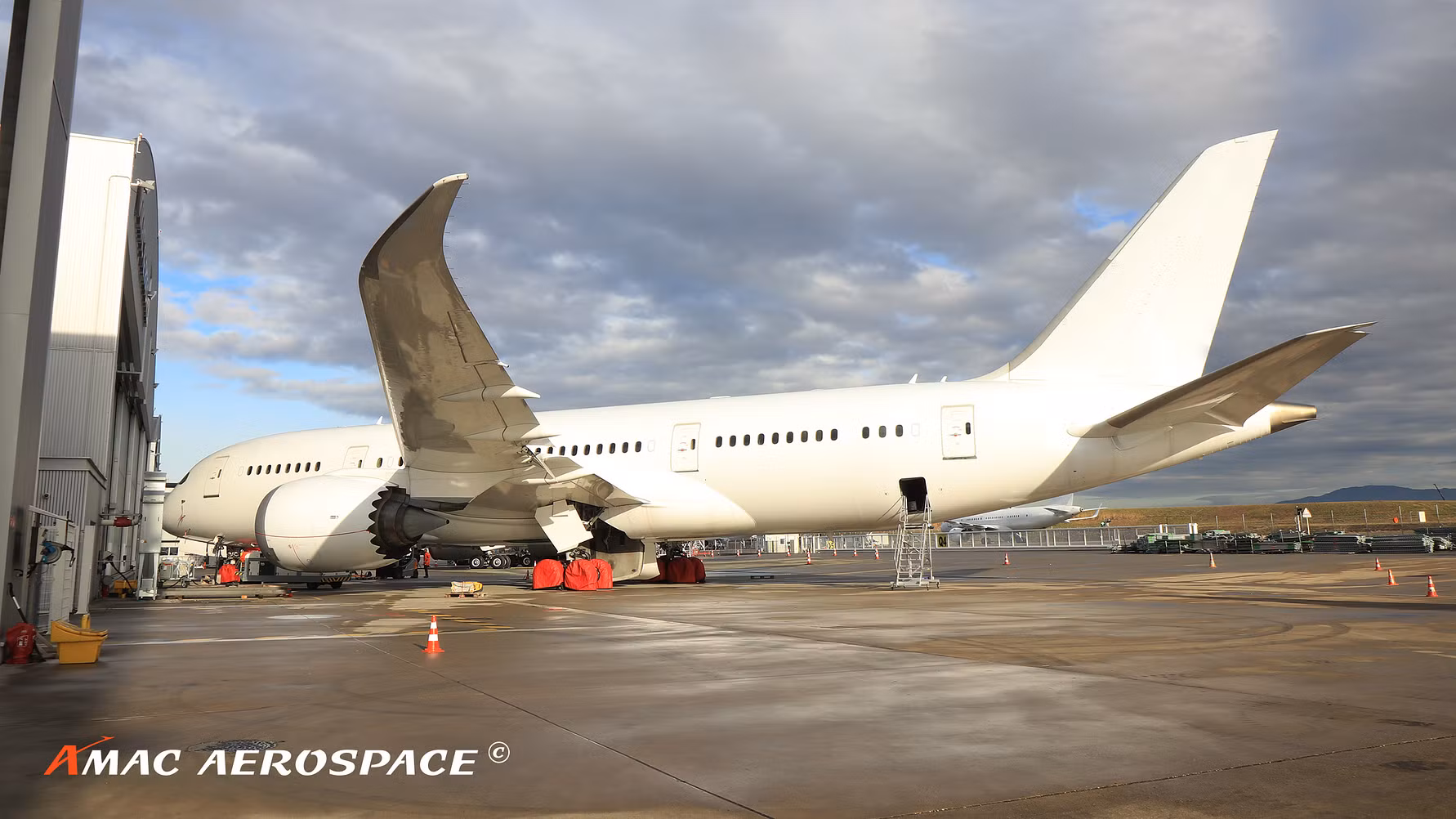 White Boeing BBJ 787 business jet parked on an airport ramp at dusk