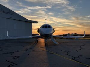 Dassault Falcon business jet parked on ramp at sunset outside hangar
