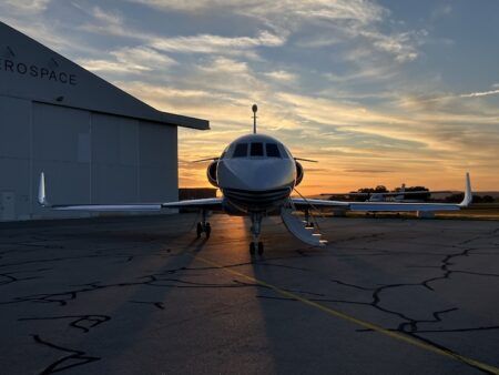 Dassault Falcon business jet parked on ramp at sunset outside hangar