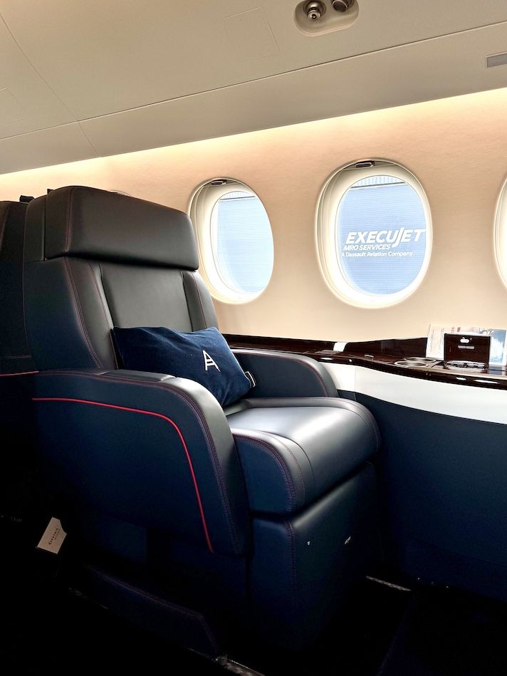 Navy leather seat with monogrammed pillow inside private jet cabin