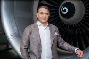 Portrait of Žilvinas Lapinskas standing in front of a jet engine in a maintenance hangar